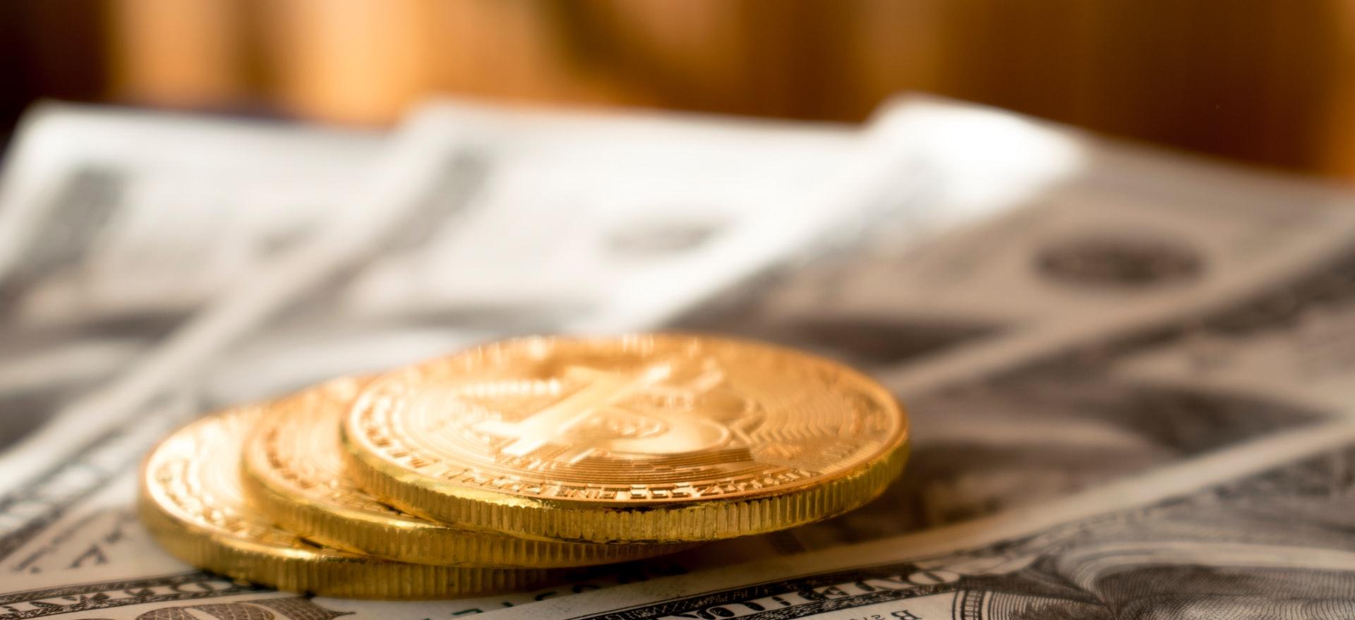 three round gold-colored coins on 100 US dollar banknotes